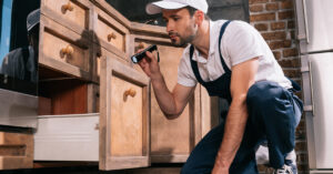 Man inspecting kitchen cabinets and drawers.