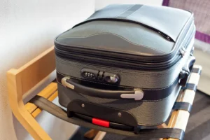 A gray suitcase on a suitcase rack to keep it off the ground in a hotel room.