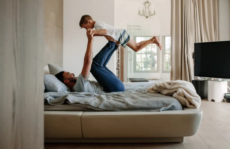 A Father and Son Play in Bed