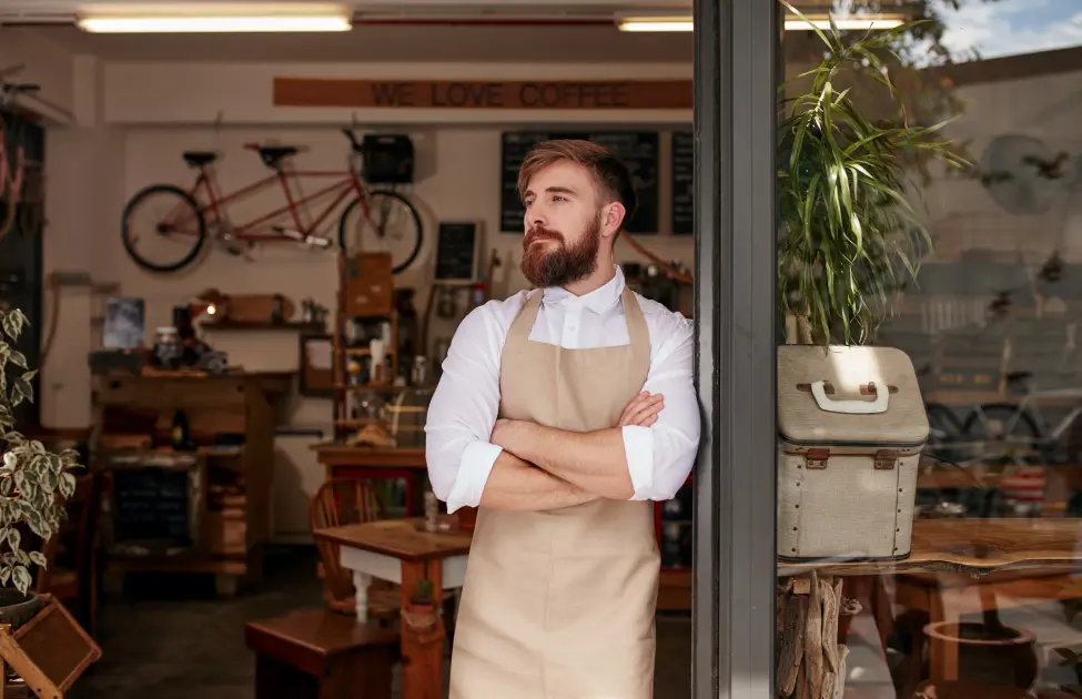 Small business owner stands outside coffee shop. Contact Twin Forks Pest Control to get rid of unwanted pests from your New York business.