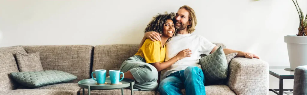 Happy new homeowners sitting on the couch after pest treatment in Long Island
